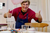 Köchin vor gedeckten Tisch mit guter Laune