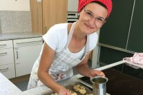 Frau am Herd bestreicht Hefegebäck mit flüssiger Butter
