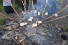 Pfannen mit langem Holzstiel überm Lagerfeuer