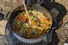 großer Topf Gemüsesuppe überm Lagerfeuer