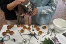Kinderhände gießen aus einem kleinen Topf Spitzwegerichsalbe in ein Döschen