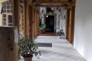 Verbindungsgang zwischen zwei Räumen mit viel Holz und Glas und Pflanzen