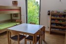 Blick in ein Zimmer mit Stockbett, Tisch, Stühlen und einem Regal voller Brettspielen