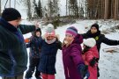 Kinder mit Helmen und einem Forstwiertschaftsmeister stehen eng beieinander und spielen das Durchforstungsspiel