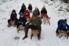 mehrere Kinder und eine Erwachsene sitzen auf Schlitten