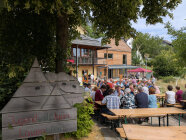 Gäste sitzen im Freien auf Bierbänken