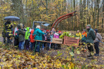 Schulklasse steht mit Förstern und Lehrern im Wald vor Schlepper