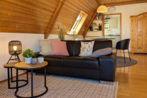 Aufgeräumte Ferienwohnung mit Sofa und Couchtisch im Vordergrund